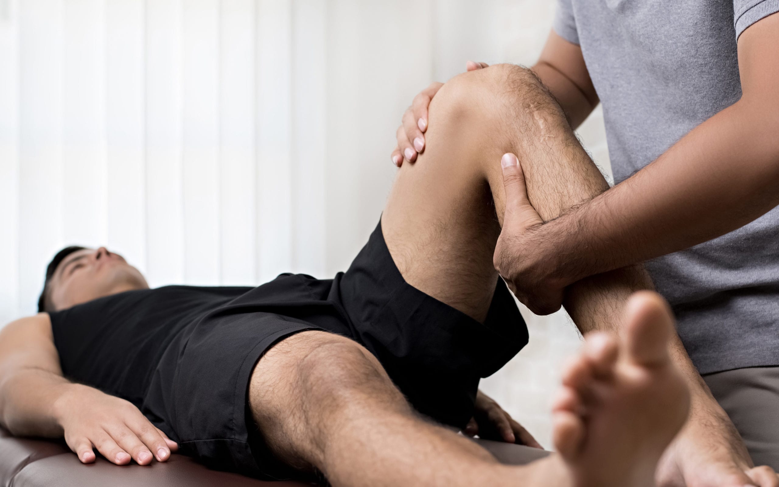 Close up of a therapist manipulating a patients knee